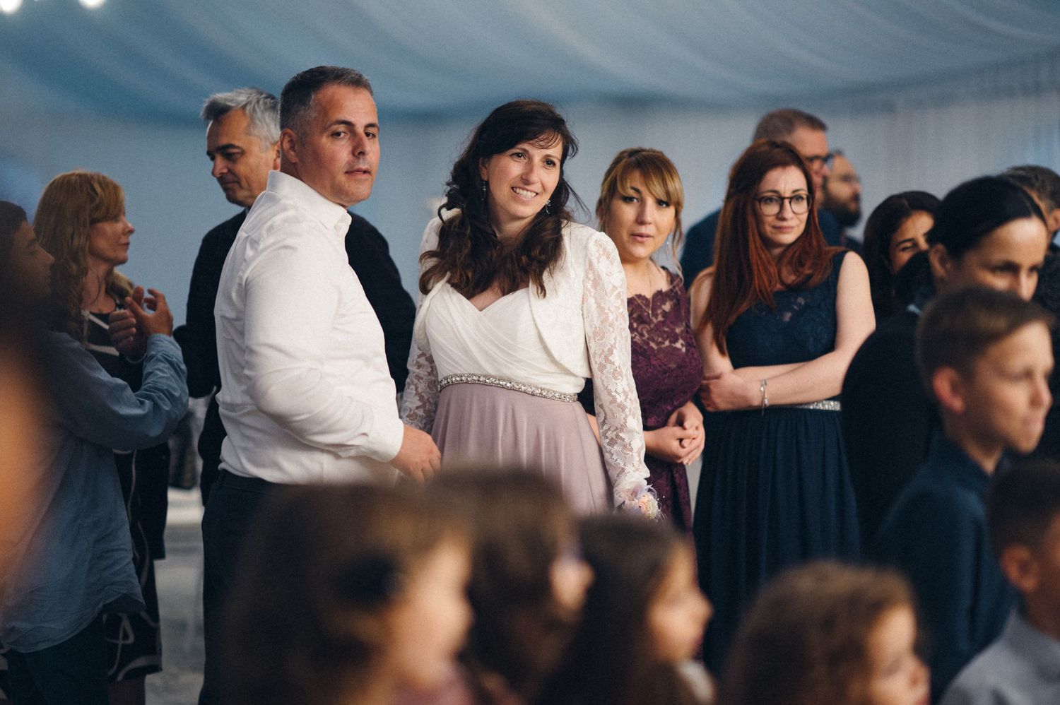 Wedding guests in formal attire gather at reception venue.