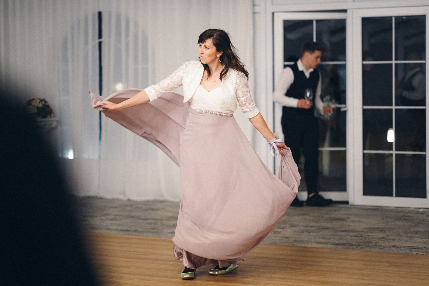 A dancer twirls their flowing pink skirt on a wooden dance floor.