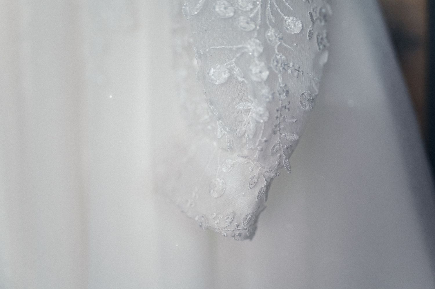 Detailed view of delicate lace pattern on white wedding dress fabric.
