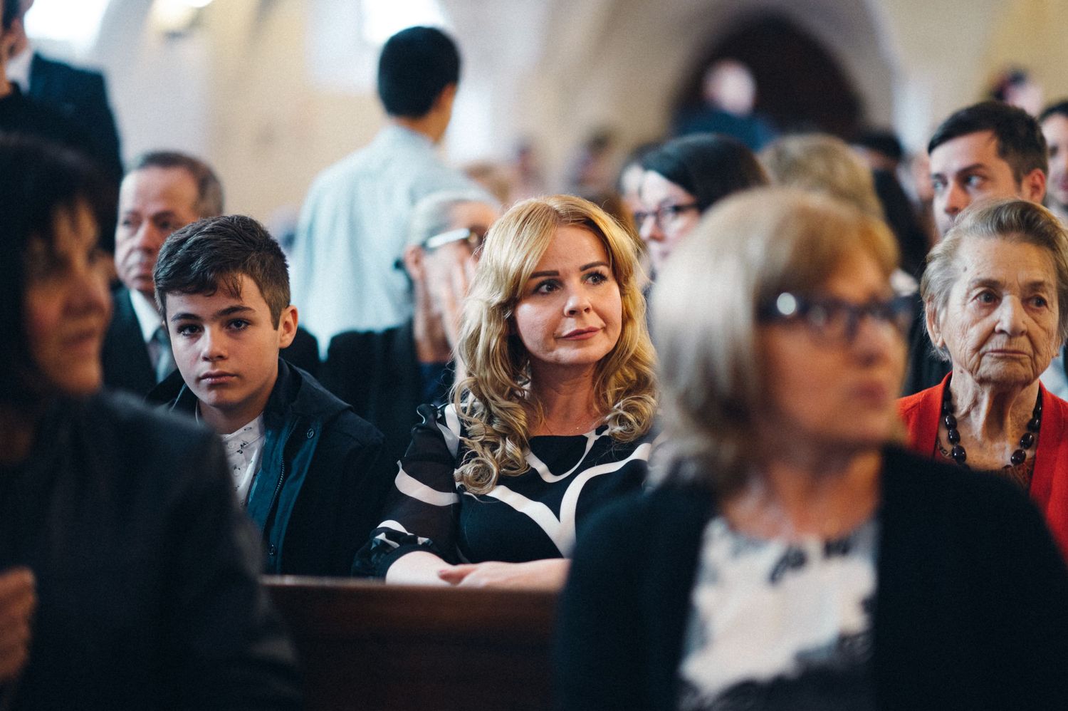 Church attendees sit attentively in wooden pews during a formal service.