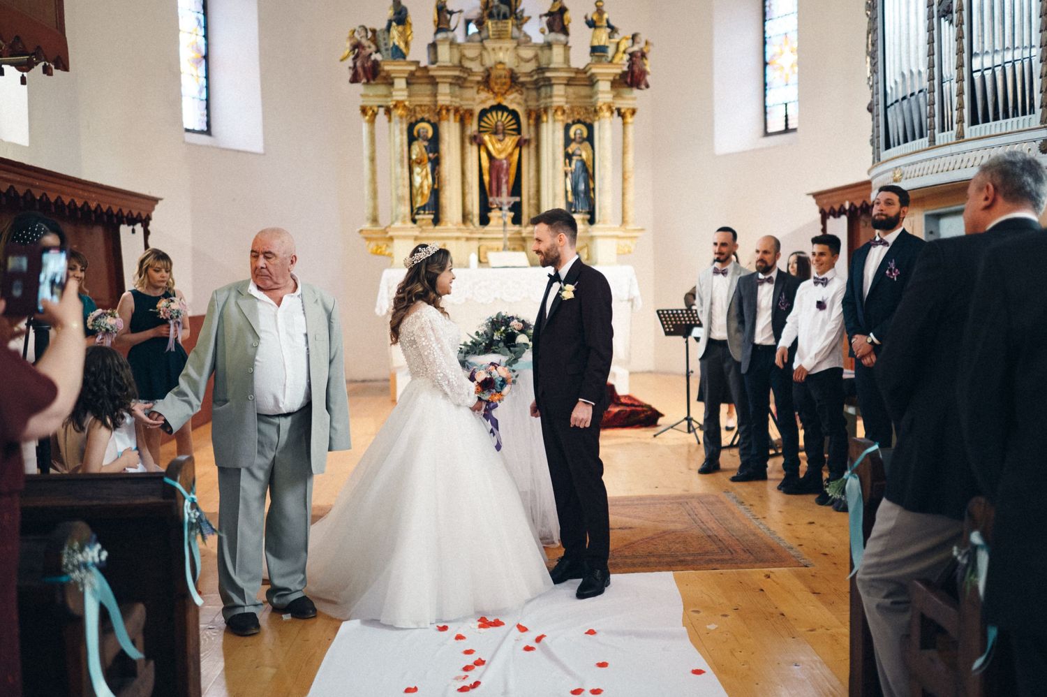 Traditional church wedding ceremony with elegant white decor and ornate religious altar.
