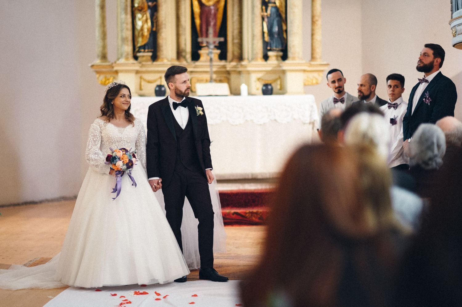 Aerial view of wedding ceremony in historic white church filled with guests.