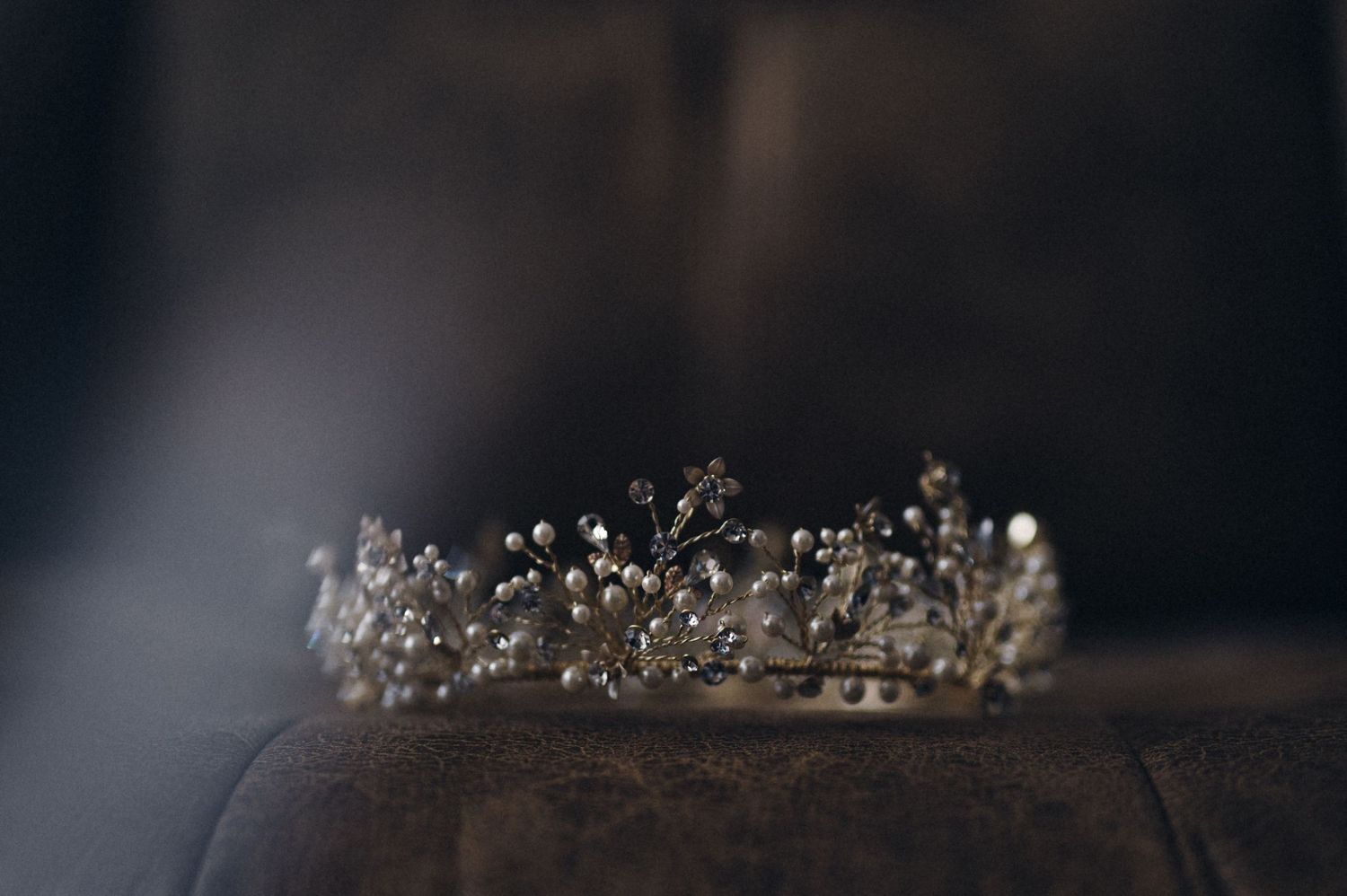 Ornate crystal and pearl bridal tiara on dark background.