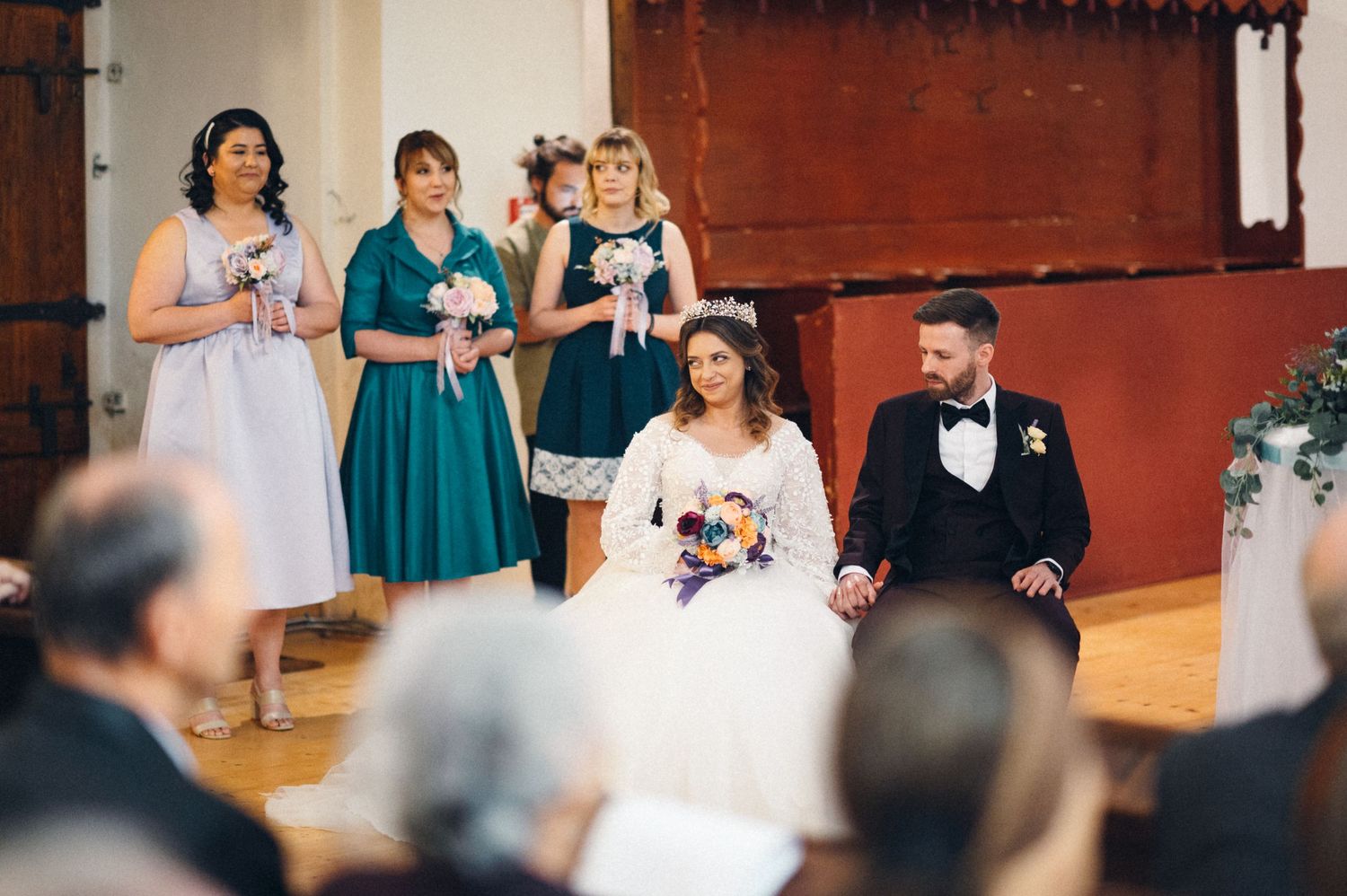 Wedding ceremony scene with bridesmaids in turquoise dresses standing beside the couple at the altar.