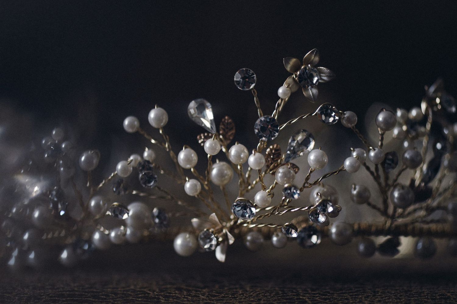 Delicate bridal hair accessory with pearl and crystal details photographed against dark background.