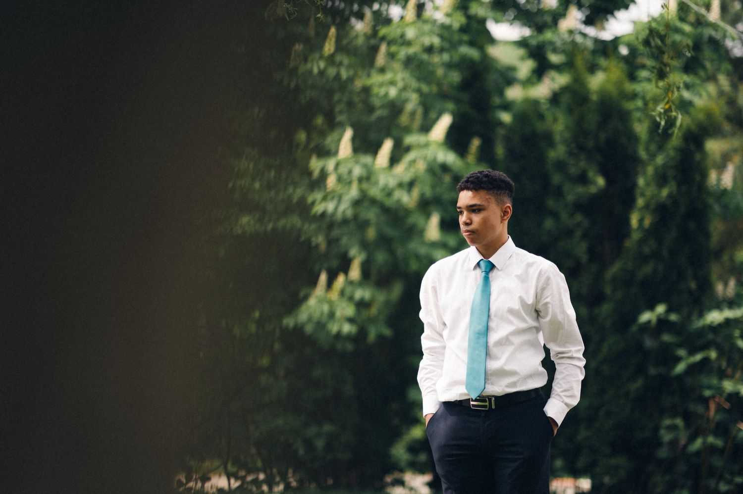 A formal portrait in a natural setting with greenery in background.