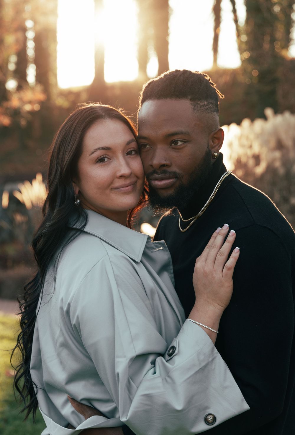 A romantic sunset portrait of a couple in casual attire embracing outdoors.