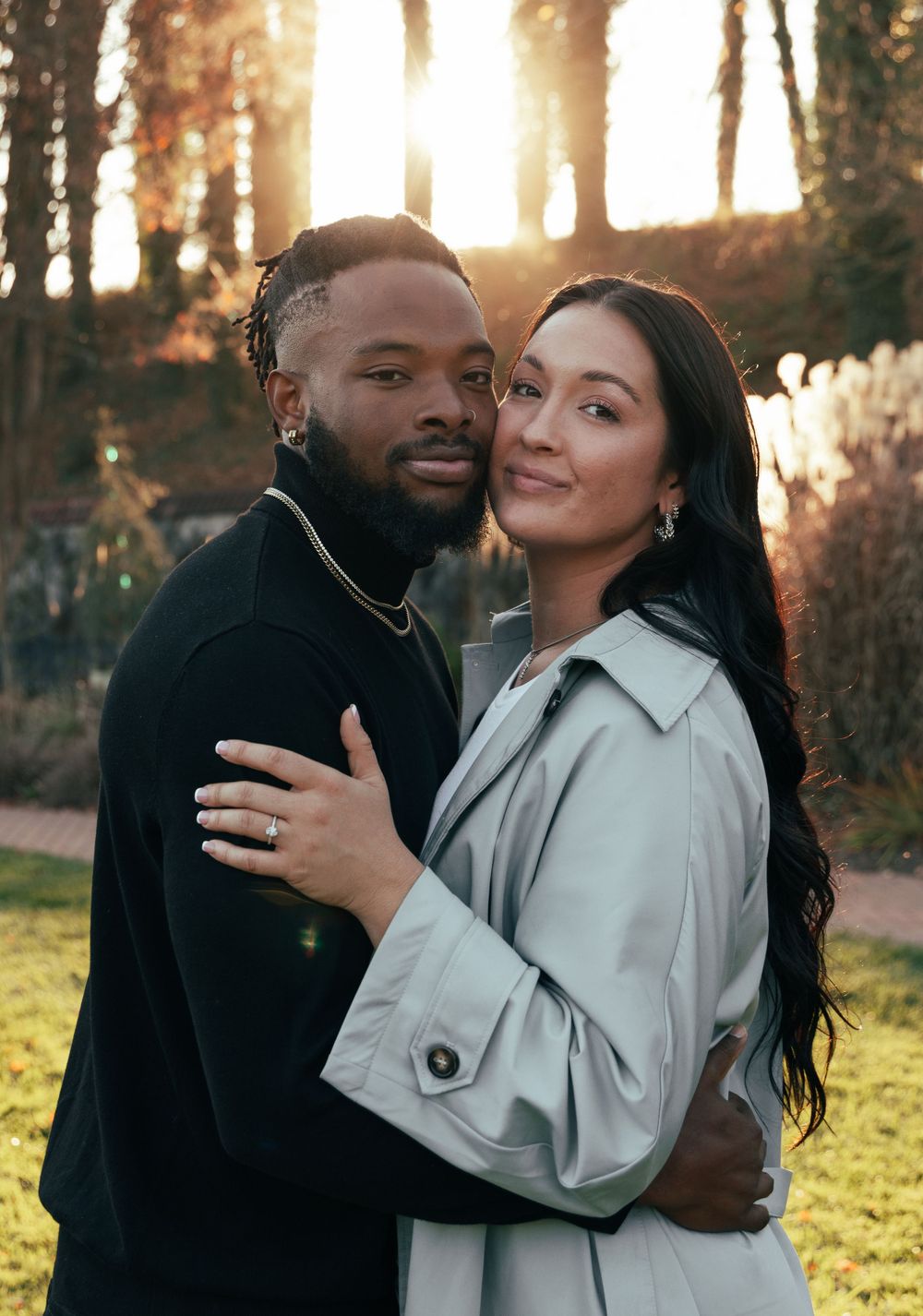 A close-up portrait of a couple in contrasting black and light gray outfits during golden hour.