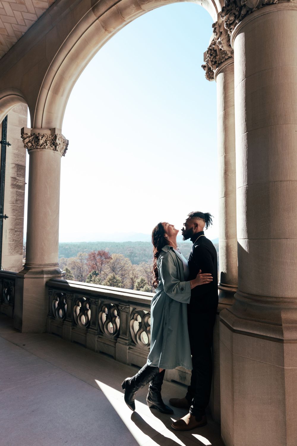Loving moment captured between a couple on a classical architecture balcony with ornate details.