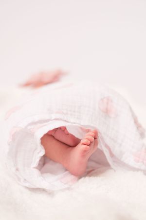photo of a little baby girl swaddled with just her little feet showing