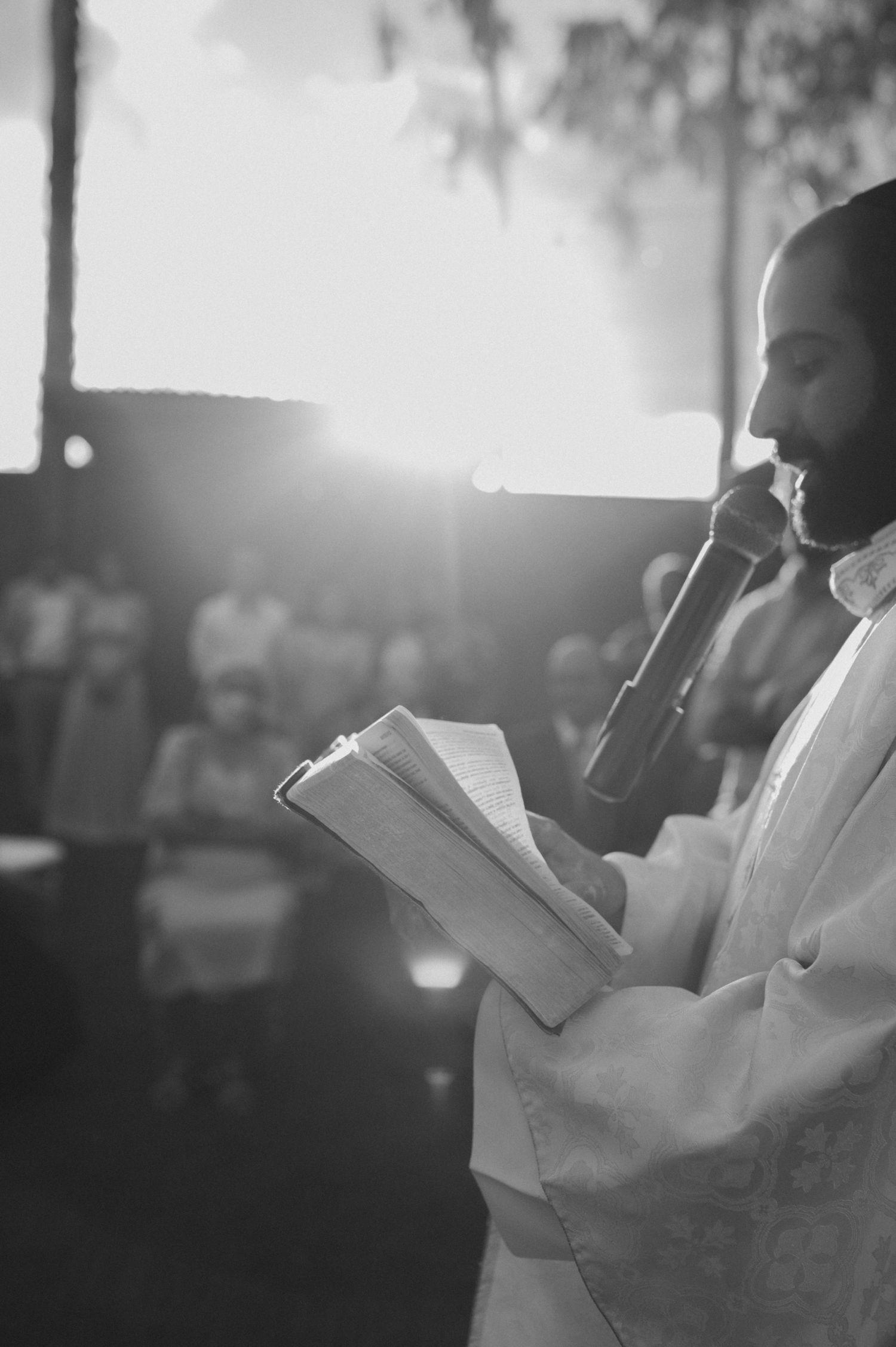 Someone in white giving a speech at an outdoor wedding ceremony during sunset.
