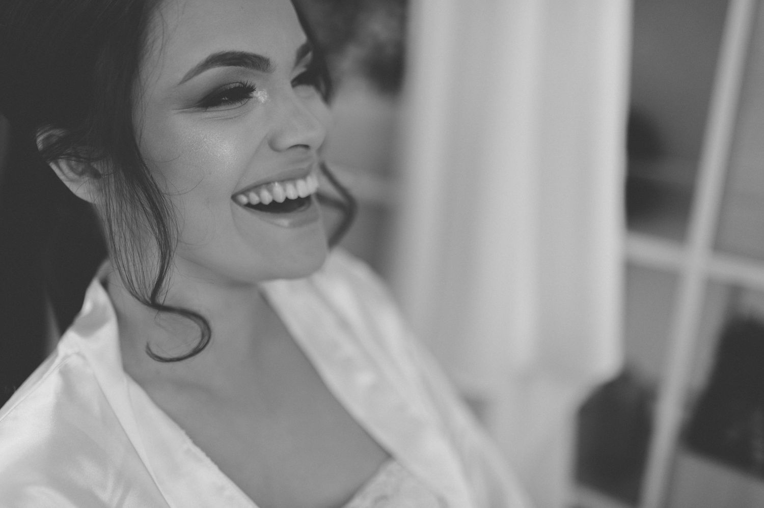 A joyful moment captured during wedding preparations with soft natural lighting.
