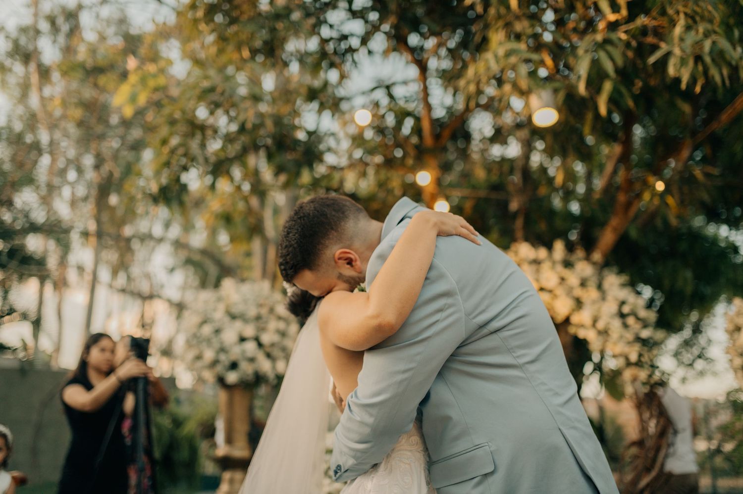 A tender embrace between newlyweds during an outdoor wedding ceremony at sunset.