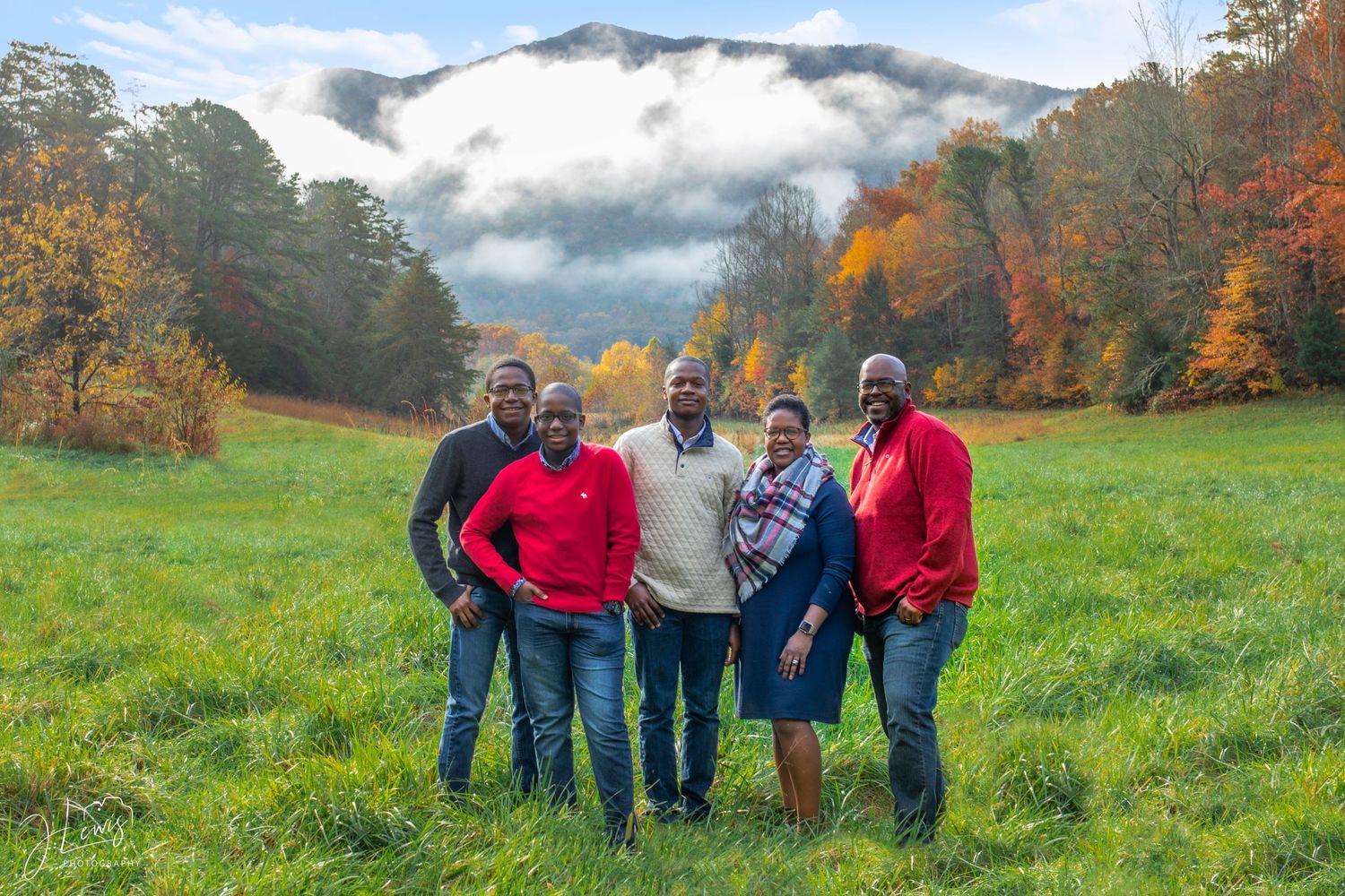 Group photo of friends in casual wear standing in a mountain meadow during fall.