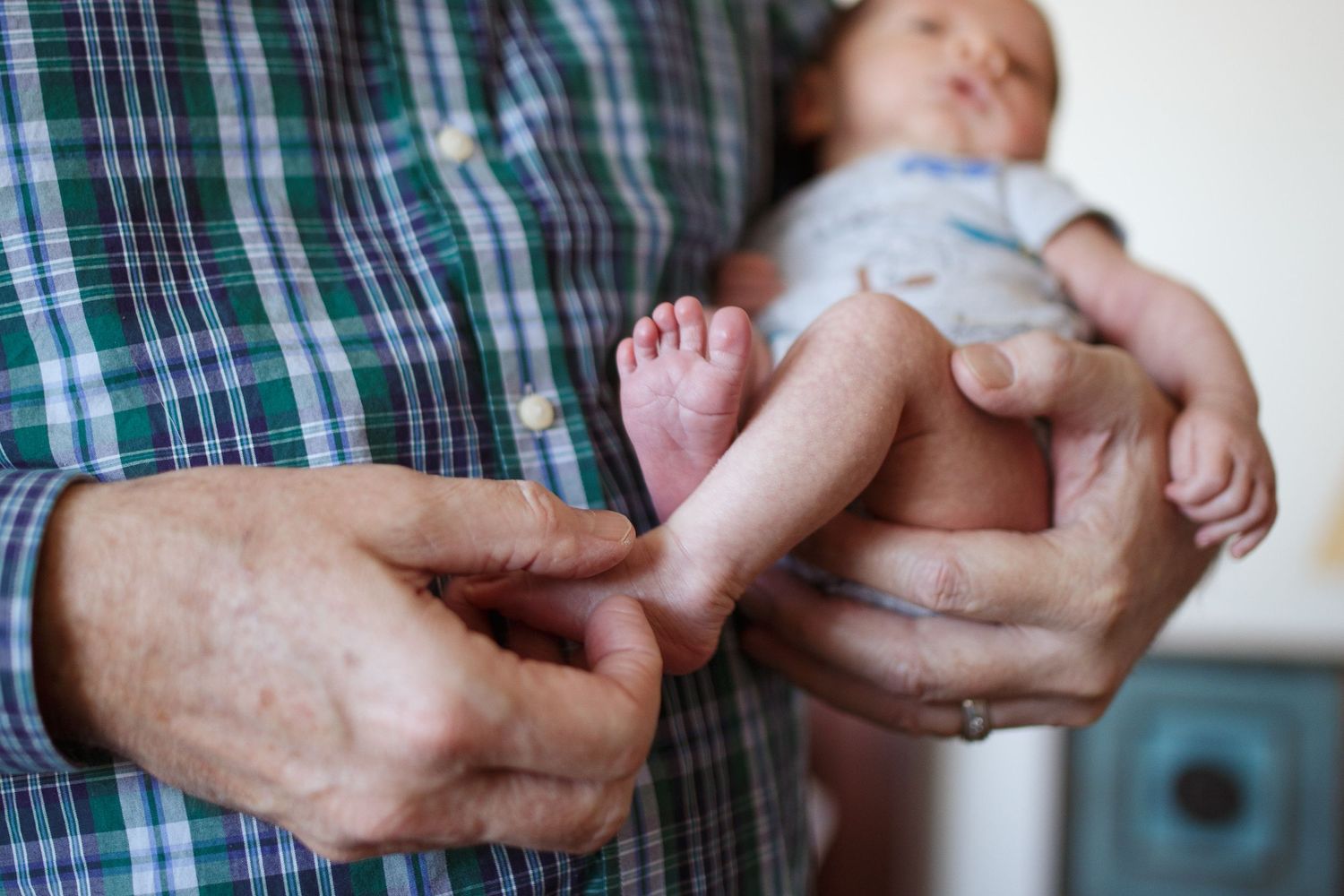 Everett Newborn photography: A grandfather hold his newborn grandson at an in-home newborn photo session