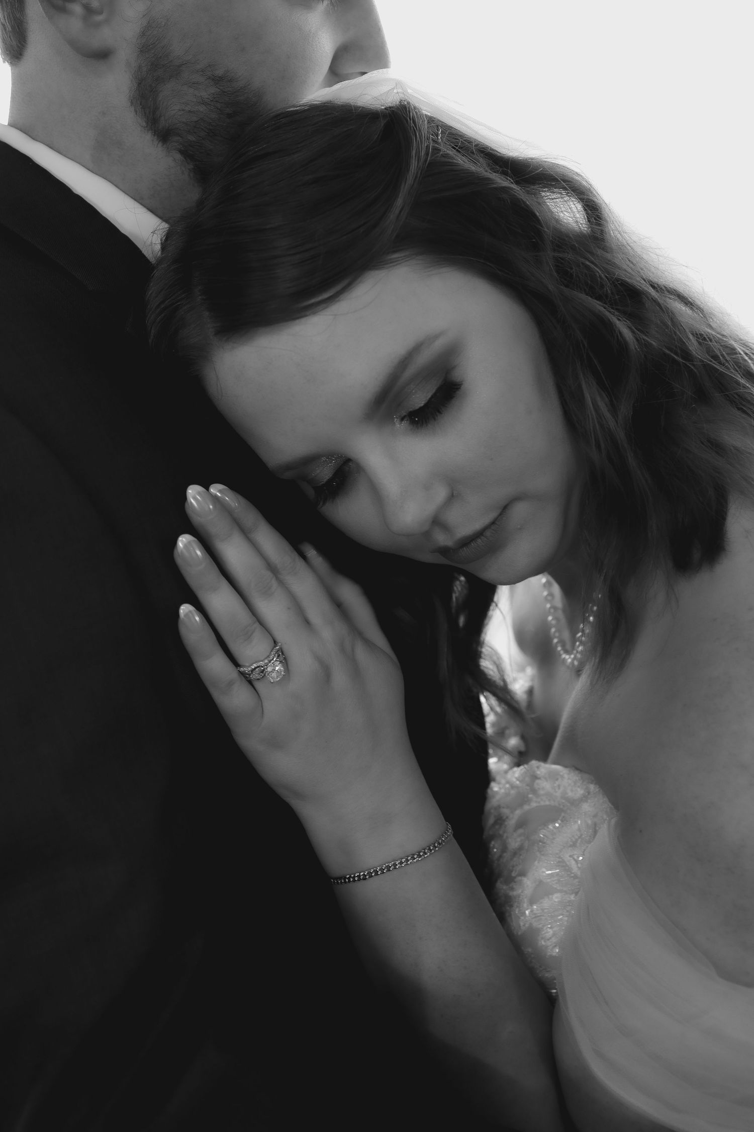 Black and white wedding portrait showing intimate moment with couple embracing and closed eyes.
