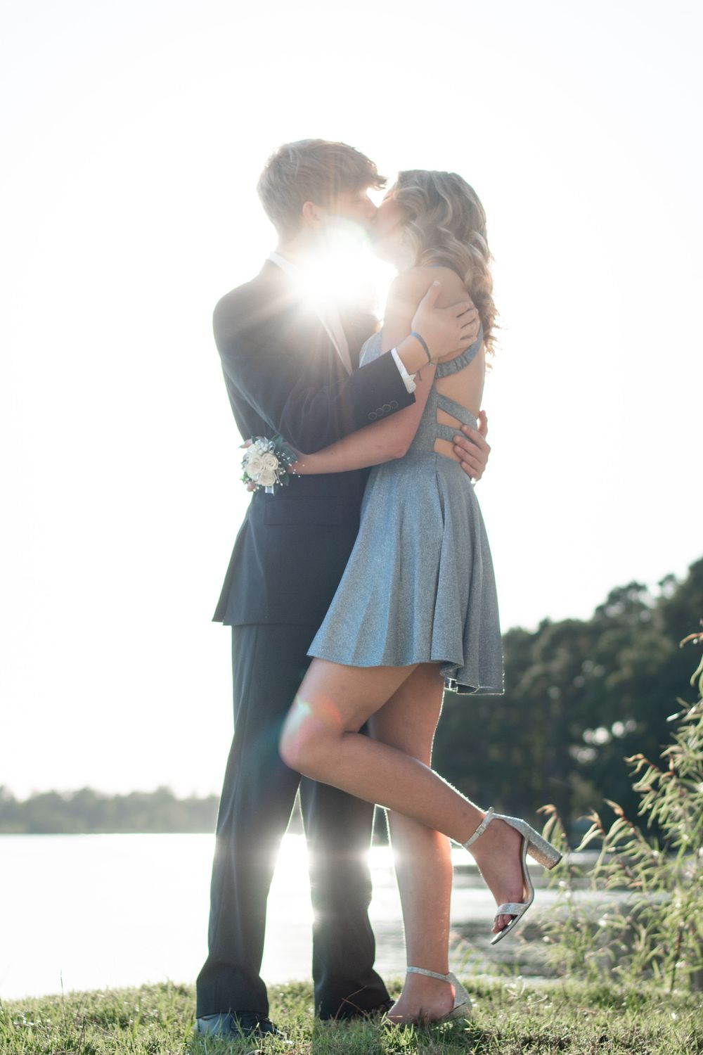 A romantic silhouette against sunset by a lake with formal attire.