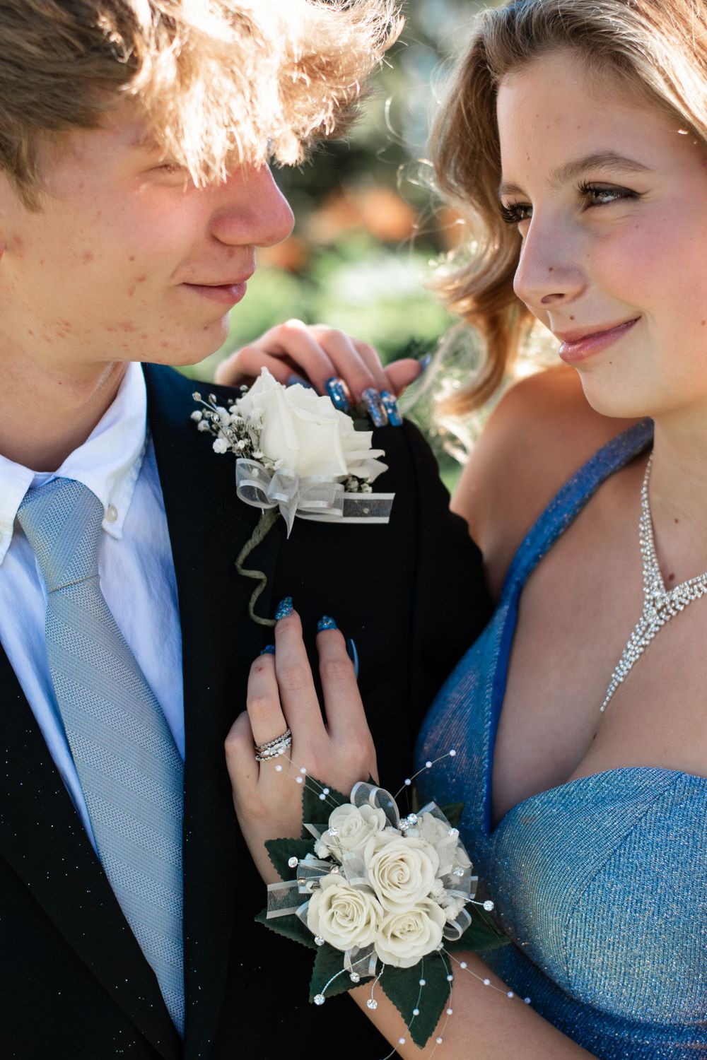 A close-up formal portrait with white rose corsage and sparkly dress details.
