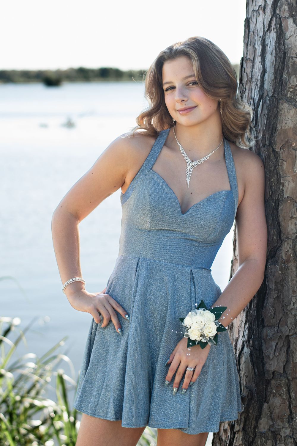 A formal dress portrait against a tree with water in the background.