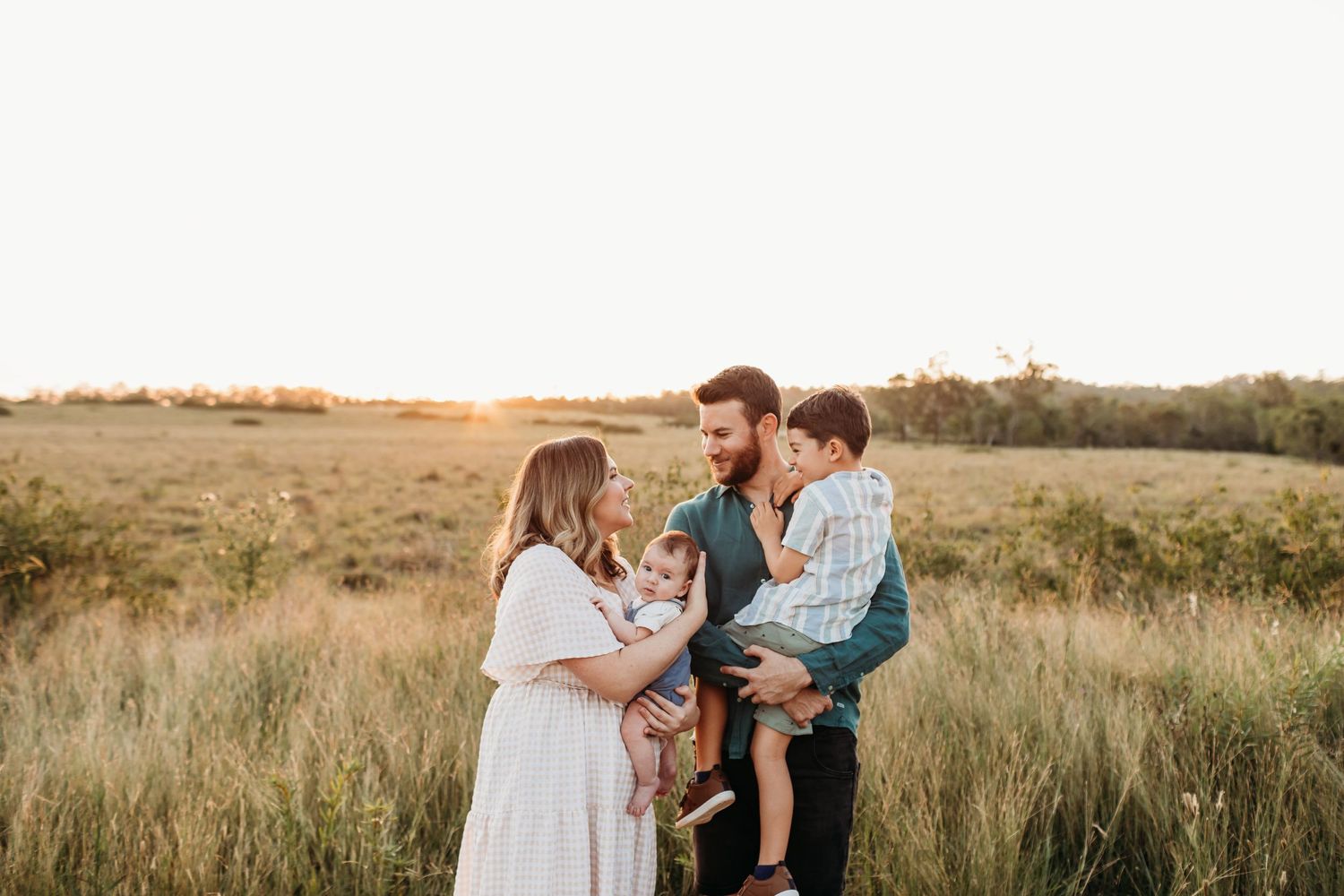 Maternity photo session in a rustic field at golden hour.