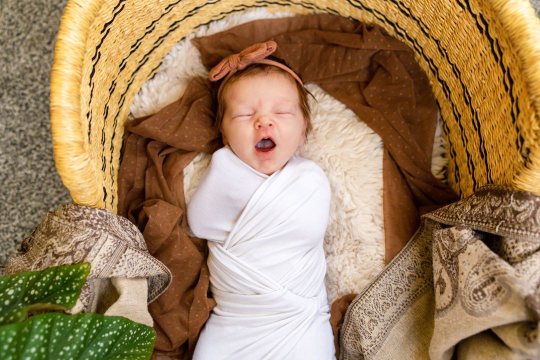 baby girl yawns in a moses basket