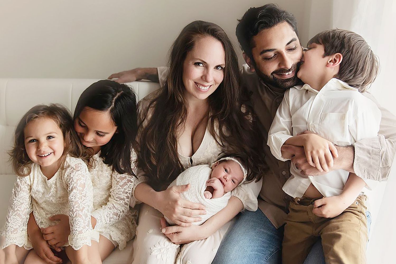 A joyful family portrait showing a growing family with multiple children.