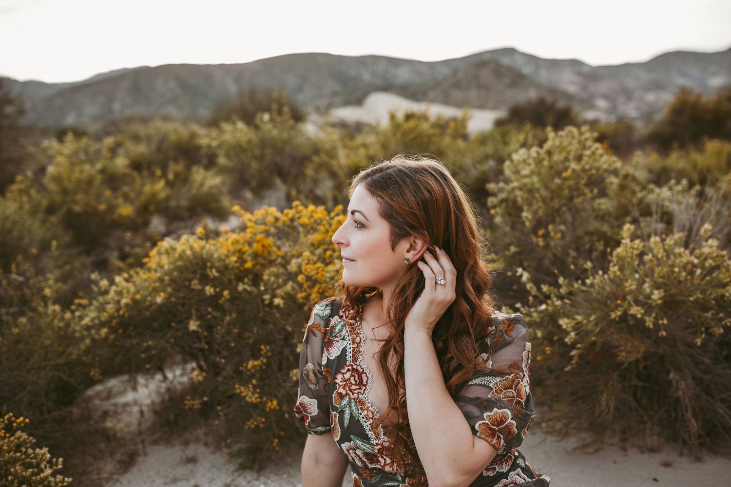 a beautiful women tucks her hair behind her ear during her family photos with heidi grace