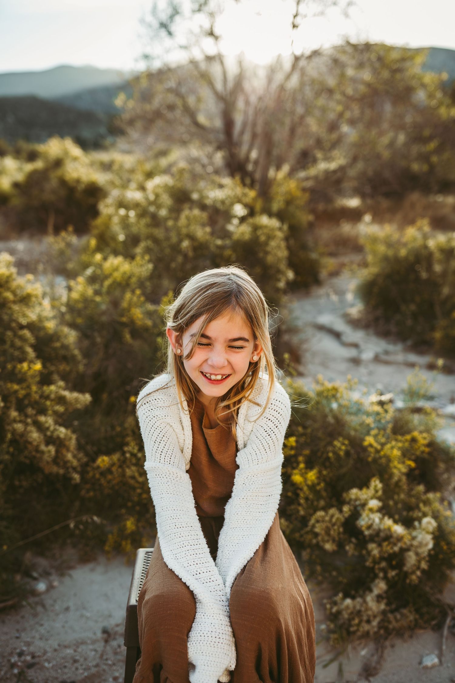 little girl sitting in the southern california desert smiling beaumont photographer heidi grace