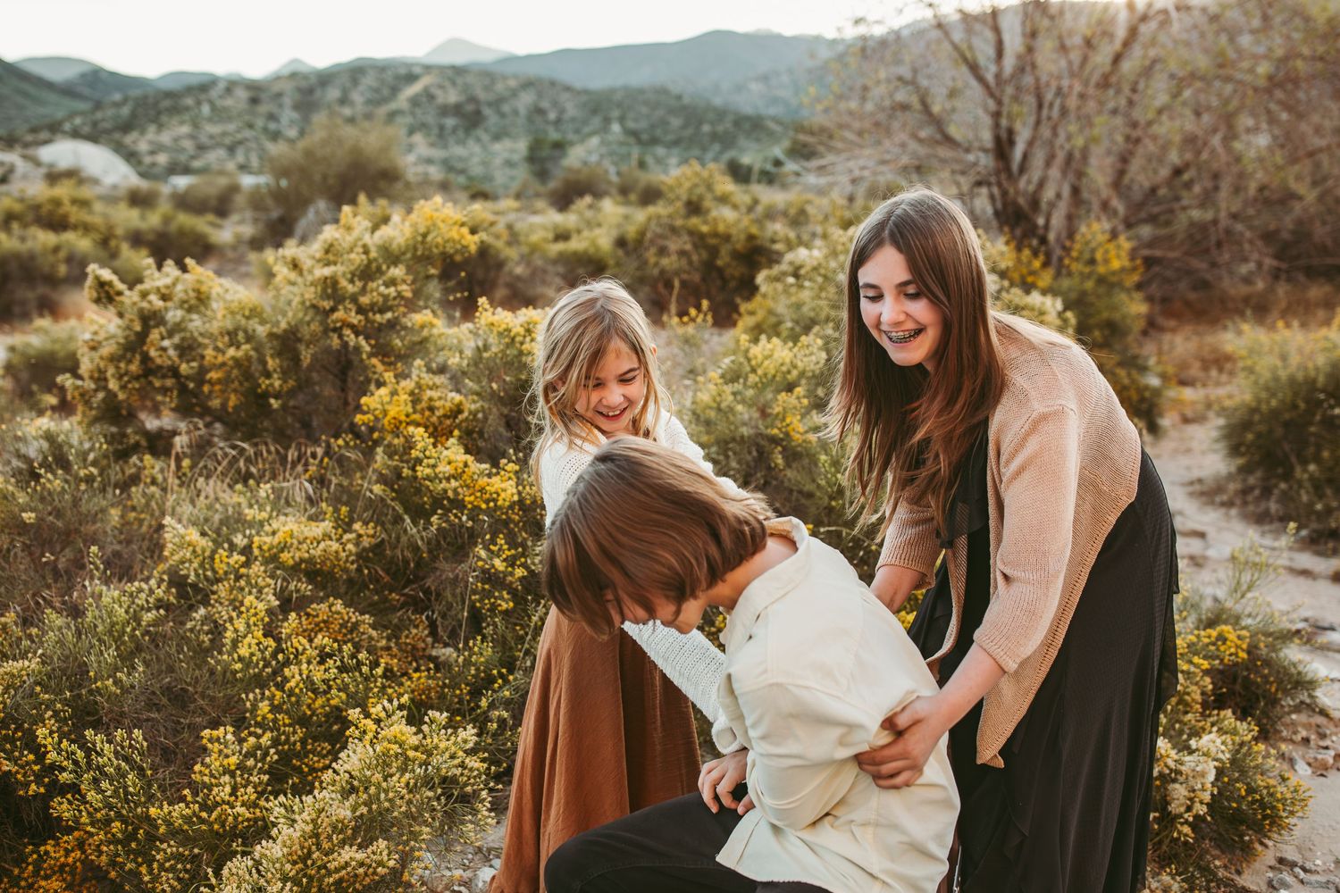 three children laugh and tickle each other during their fall family photos