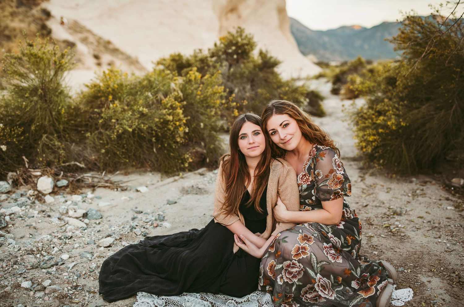 a mother and daughter sit in the desert during their family photos in the inland empire