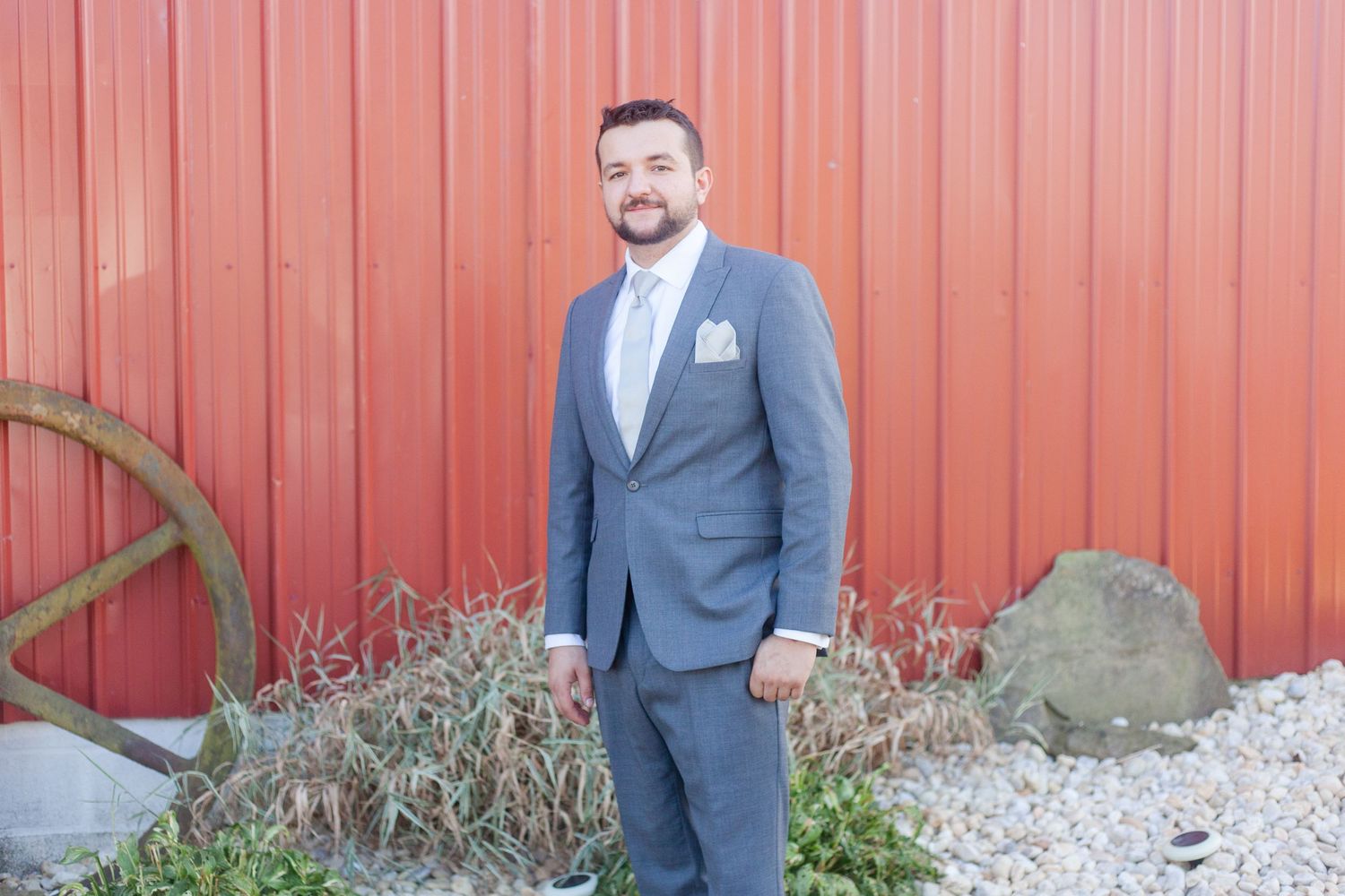 Formal portraits taken against a red barn wall with gravel ground.