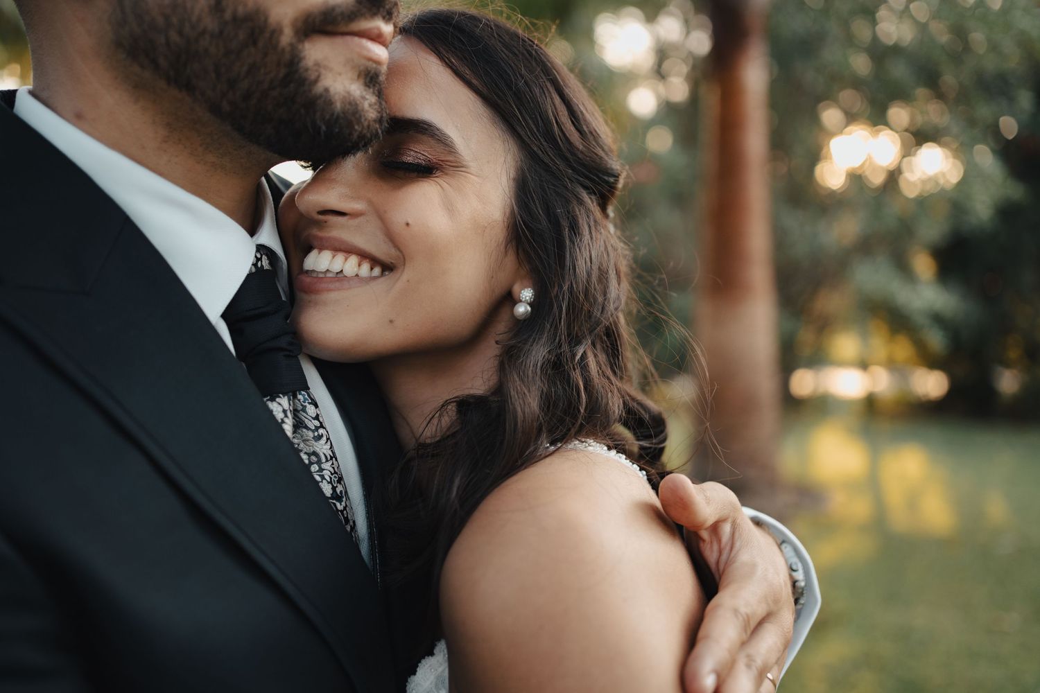 Close-up of couple embracing in formal wear during sunset outdoor photo session.