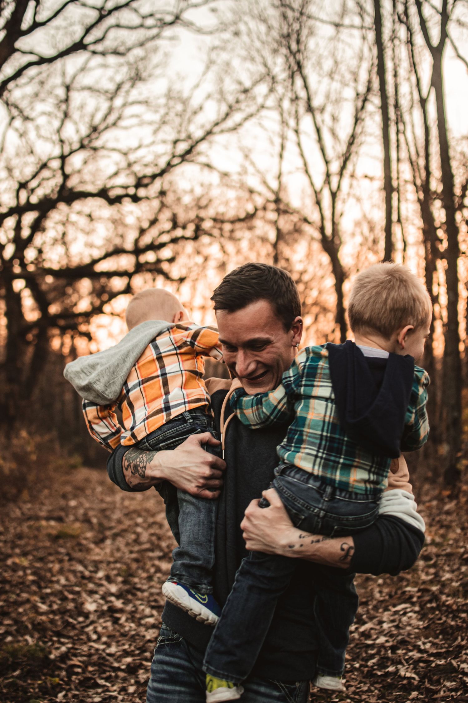 Playful moments in the woods during golden hour as children are held and laughed with.