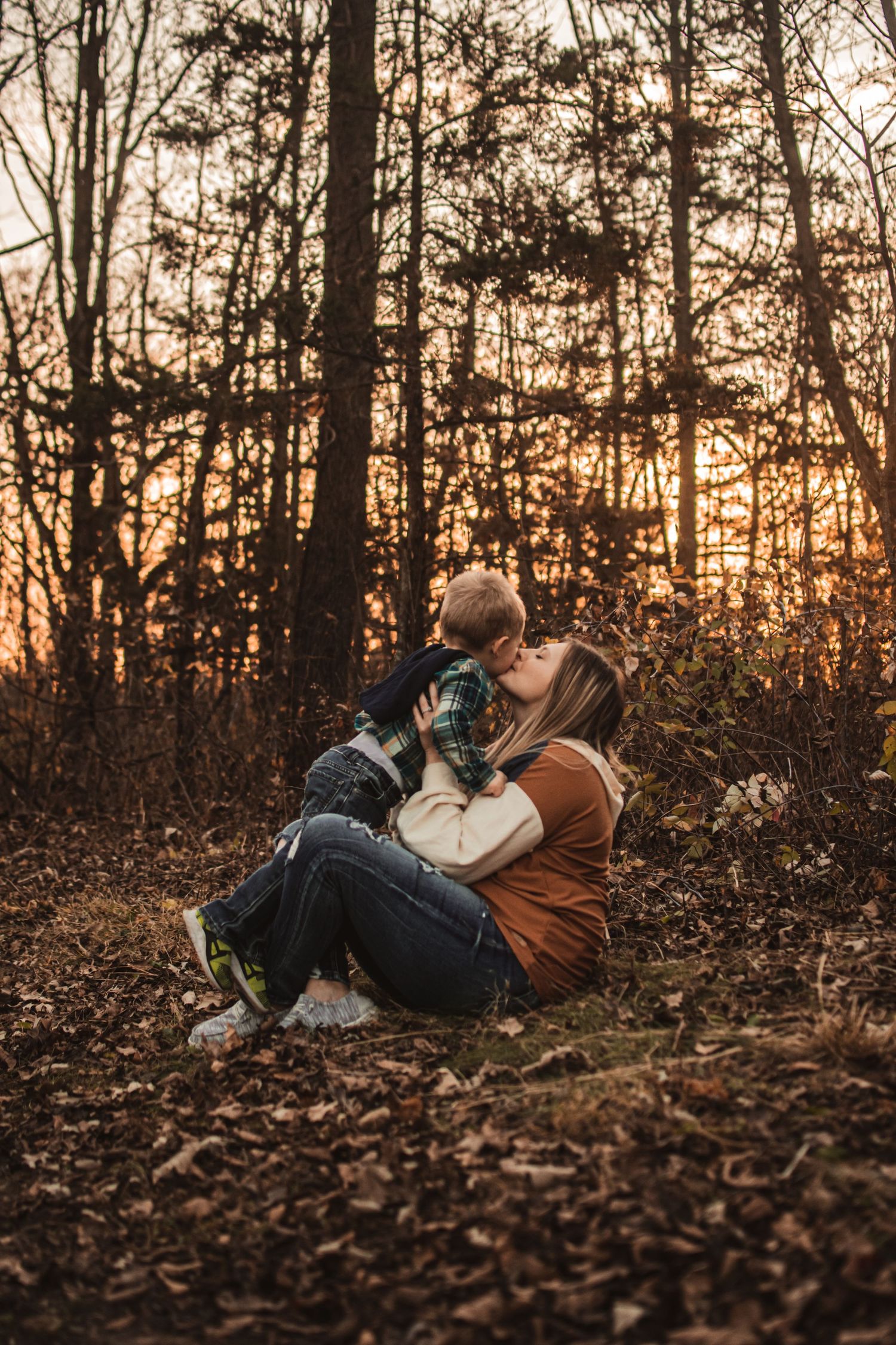 Tender moment shared on fallen leaves in an autumn forest at sunset.
