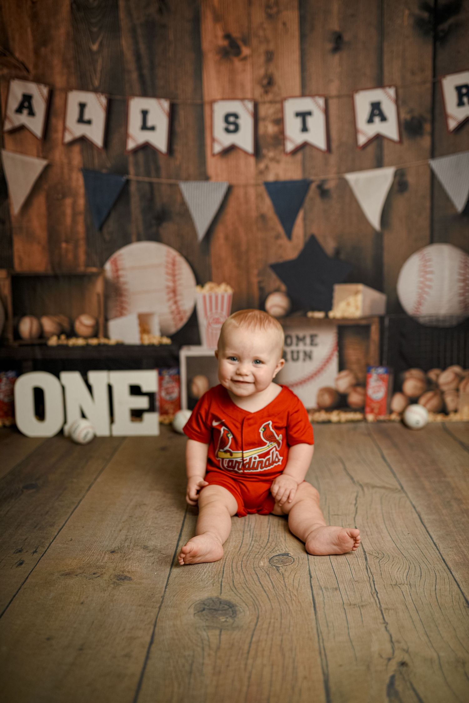 Baseball themed first birthday setup with banners and decorations on wooden floor.