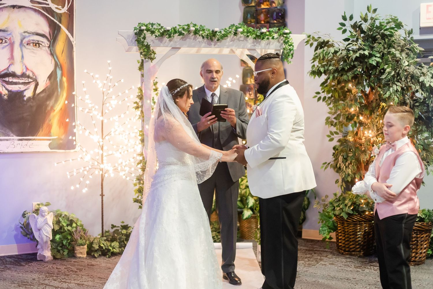 A romantic wedding ceremony moment under twinkling lights and greenery decorations.