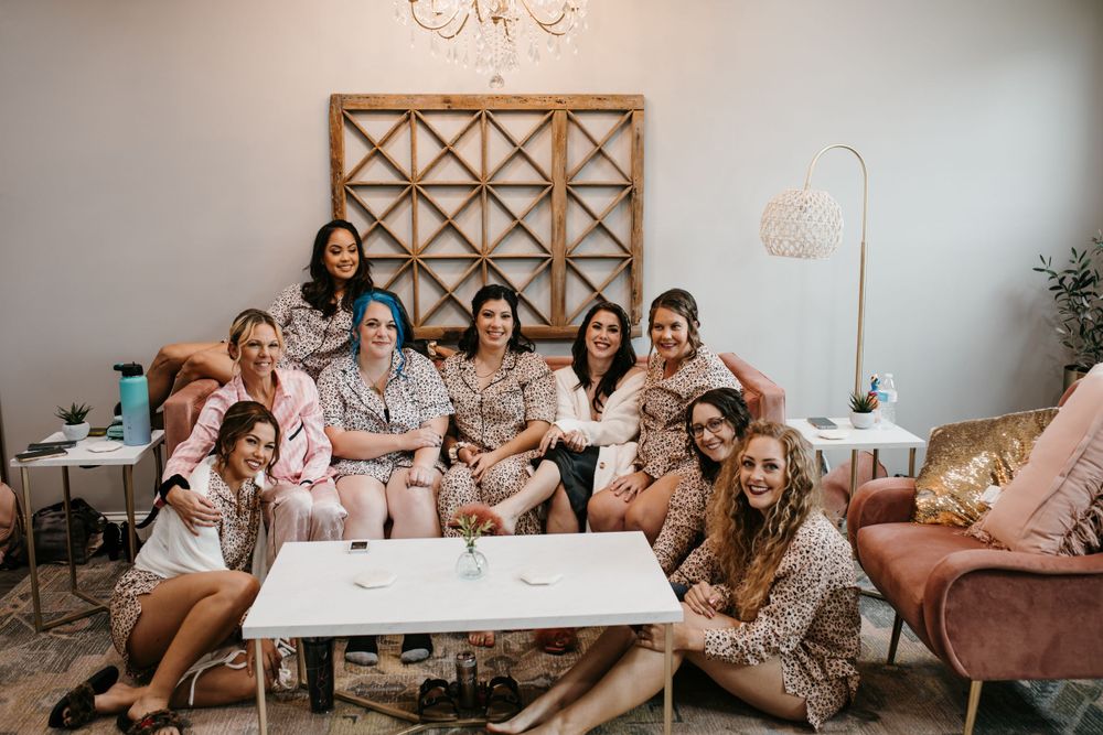 Bridesmaids in coordinating leopard print pajamas gather around white coffee table in stylish wedding prep room.