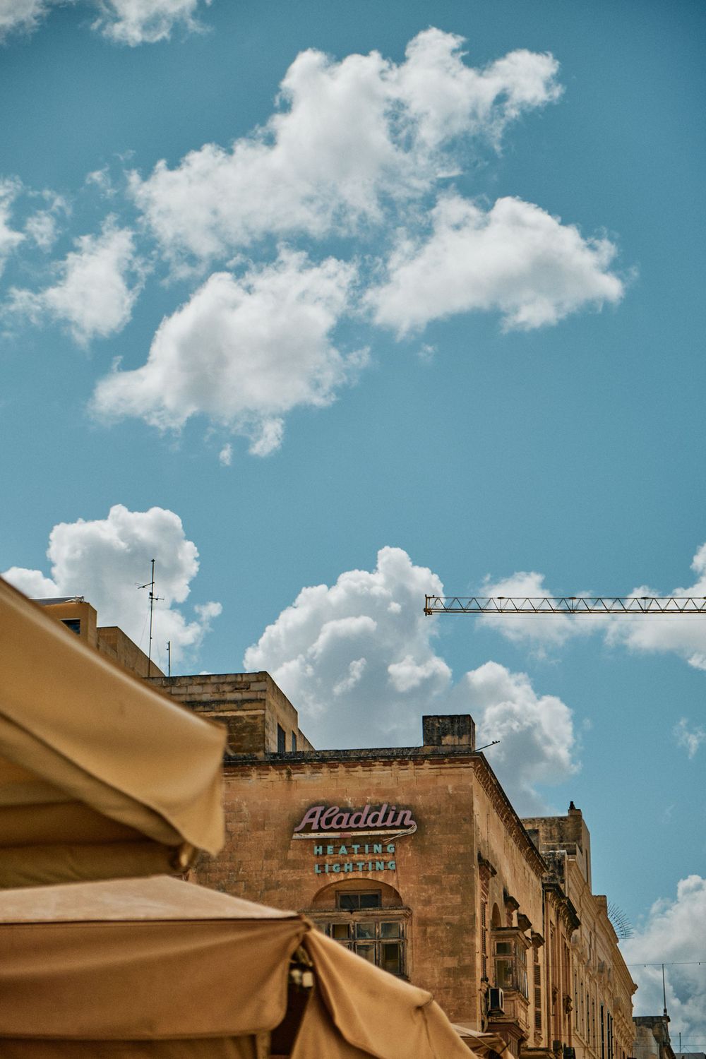 White fluffy clouds over a beige stone building with a Florians sign and market awning.