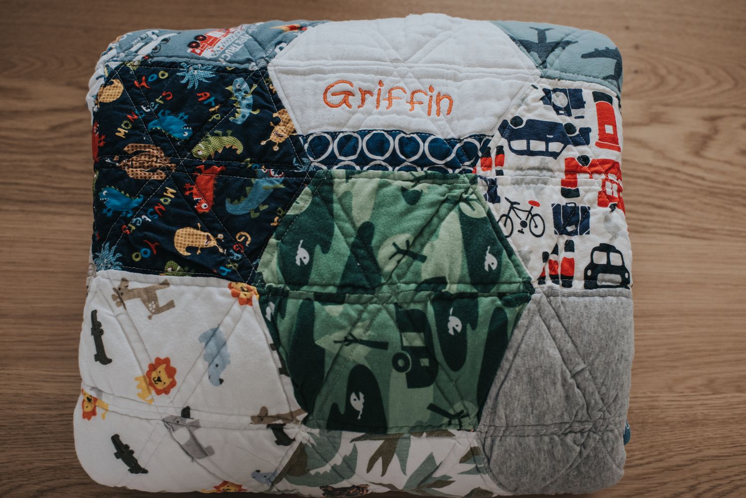 A folded up hexagon memory quilt sits on a table with the name Griffin facing up.