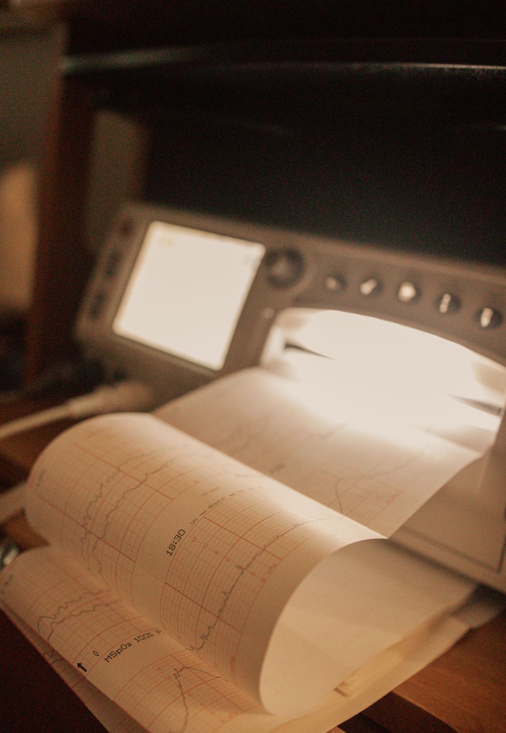 Medical charts and documents laid out on a wooden surface in dramatic lighting.