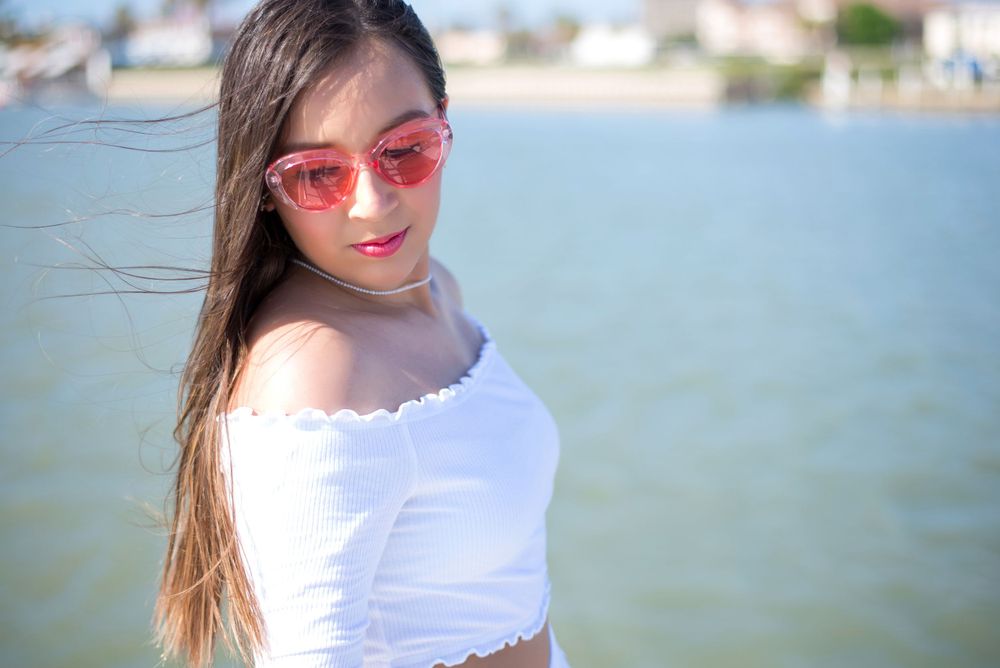 girl at sea wearing pink sunglasses. girl posing in a boat enjoying the sun. South Padre Island. Quinceanera. Wedding