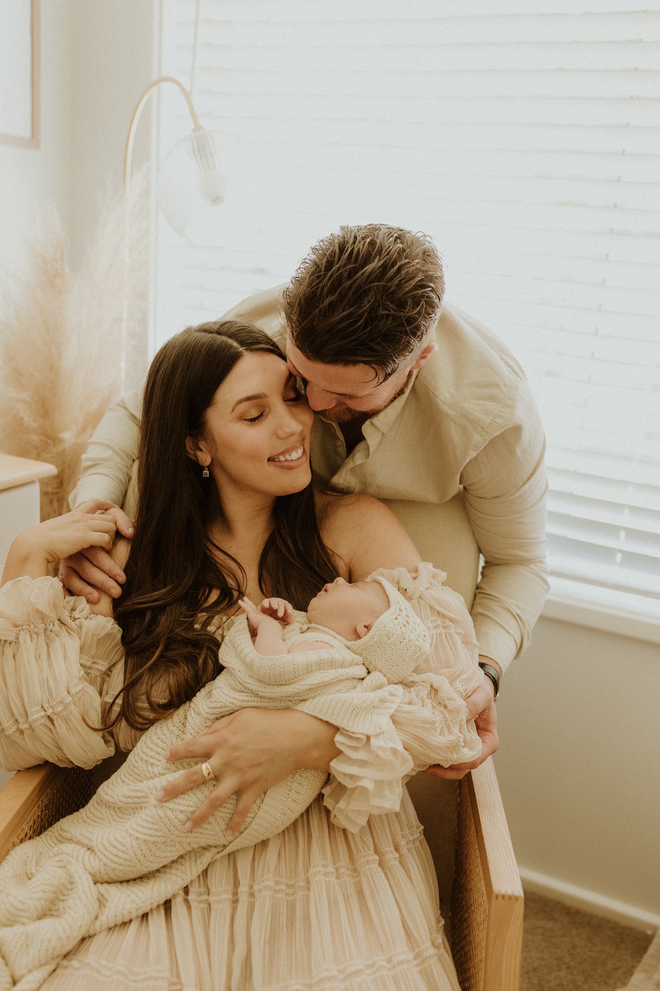 Intimate family moment with newborn baby in a cozy light-filled room.