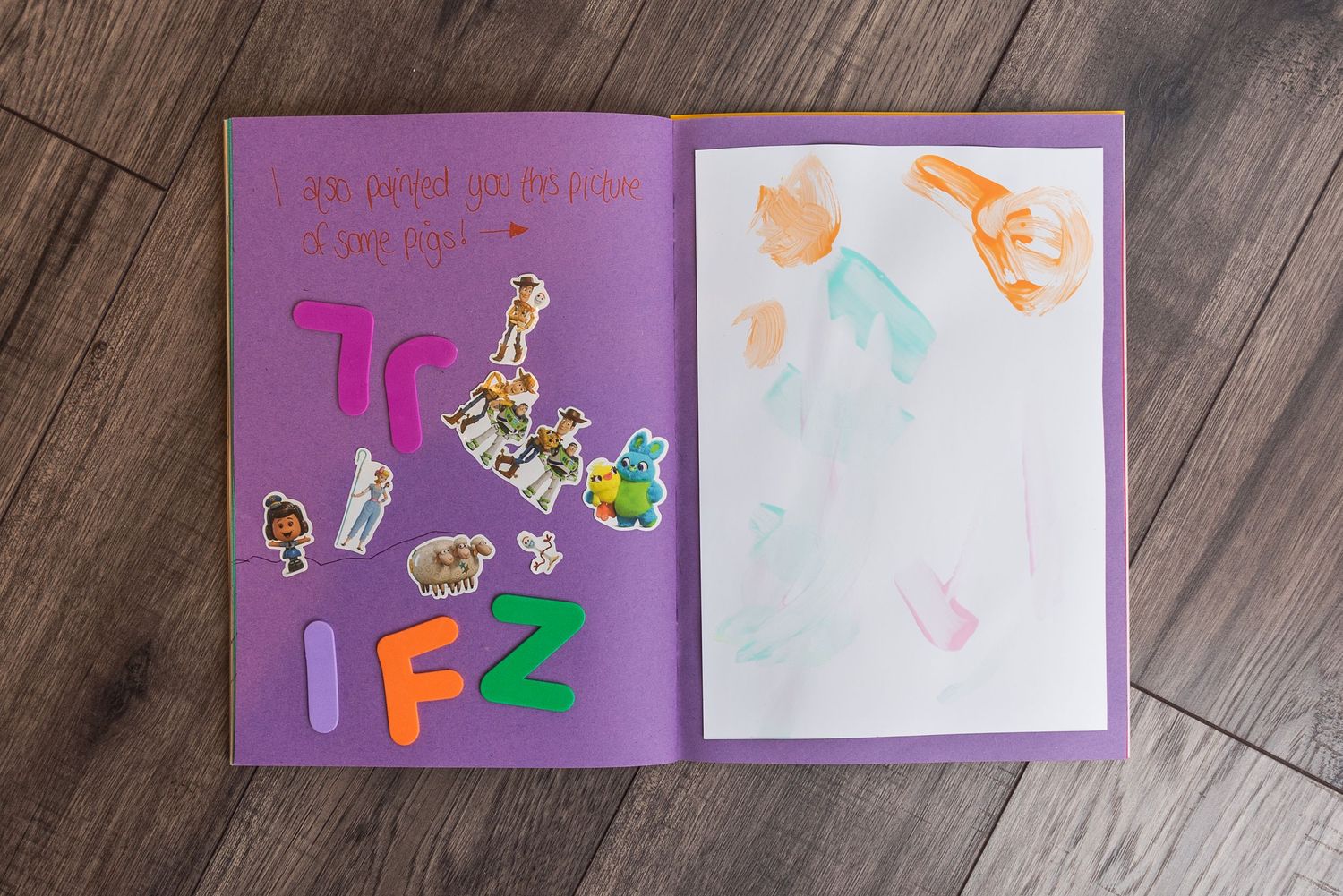 Open purple notebook with alphabet stickers and children's drawings.