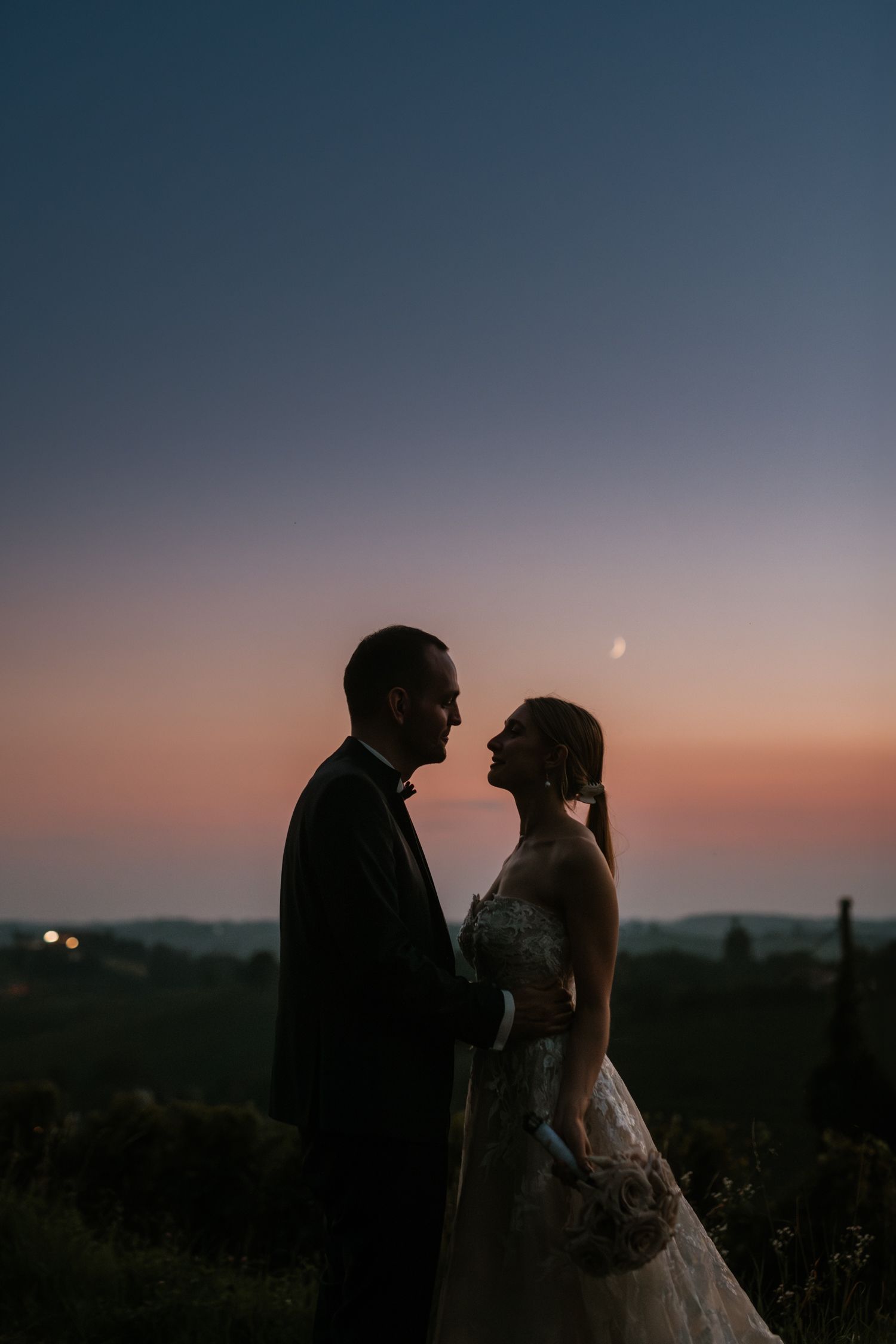 A silhouetted couple shares an intimate moment against a sunset sky.