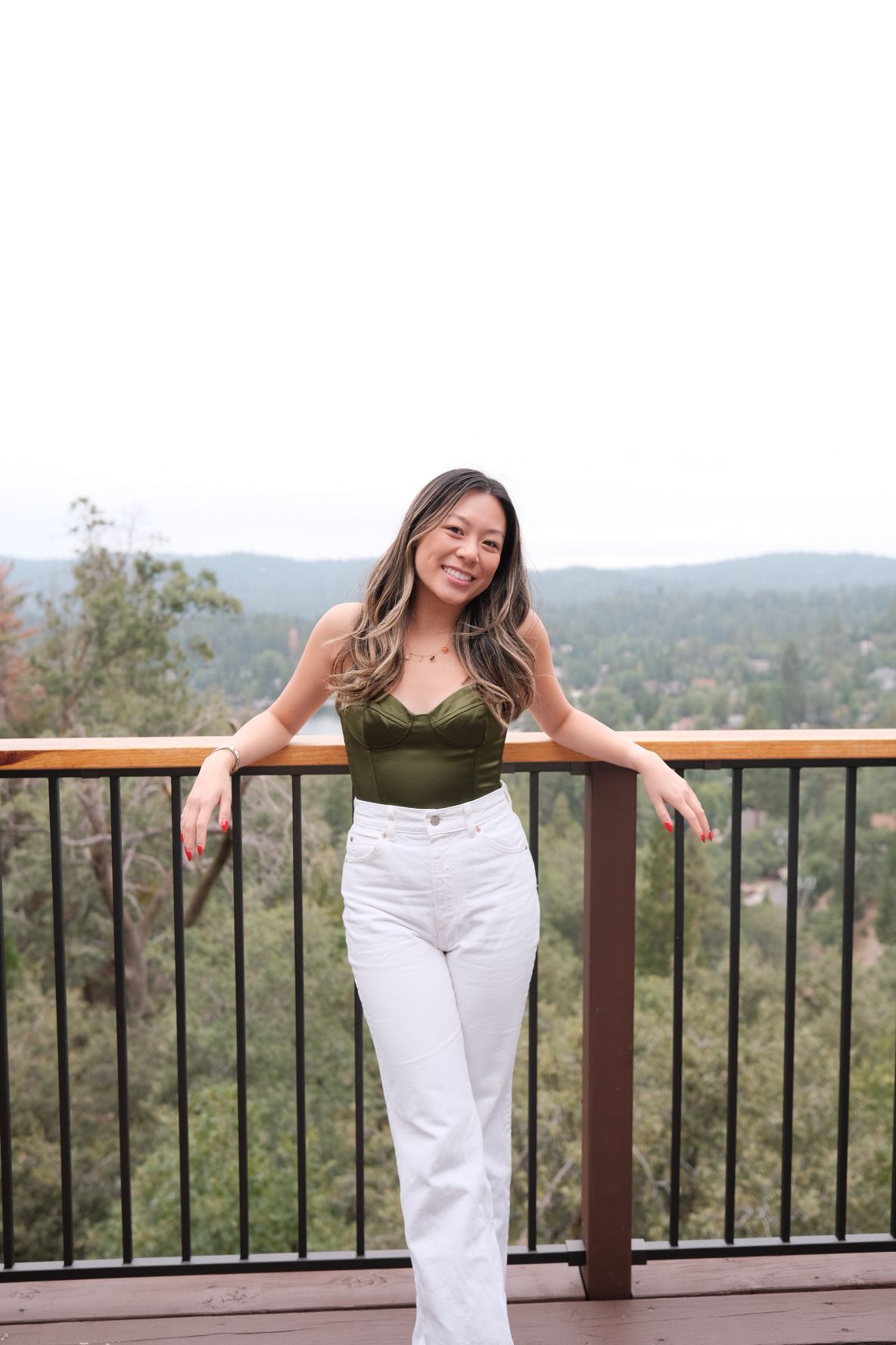 Casual portrait of someone posing on a deck overlooking a scenic mountain landscape.