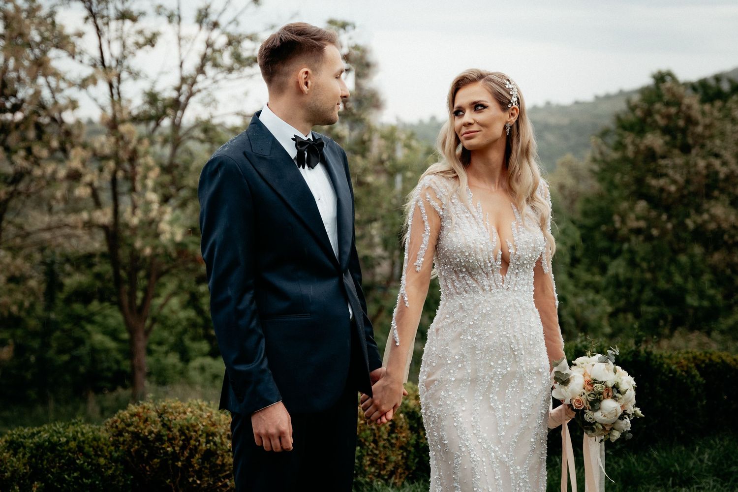 A blissful wedding couple embracing in a picturesque countryside setting, surrounded by nature's beauty.