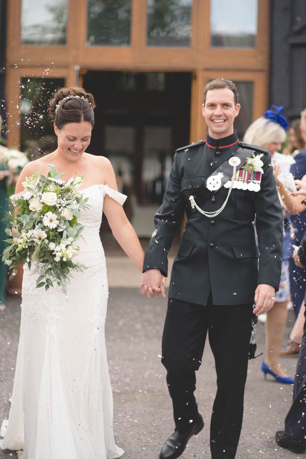 Wedding celebration outdoors with confetti and joyful moments captured in front of brick building.