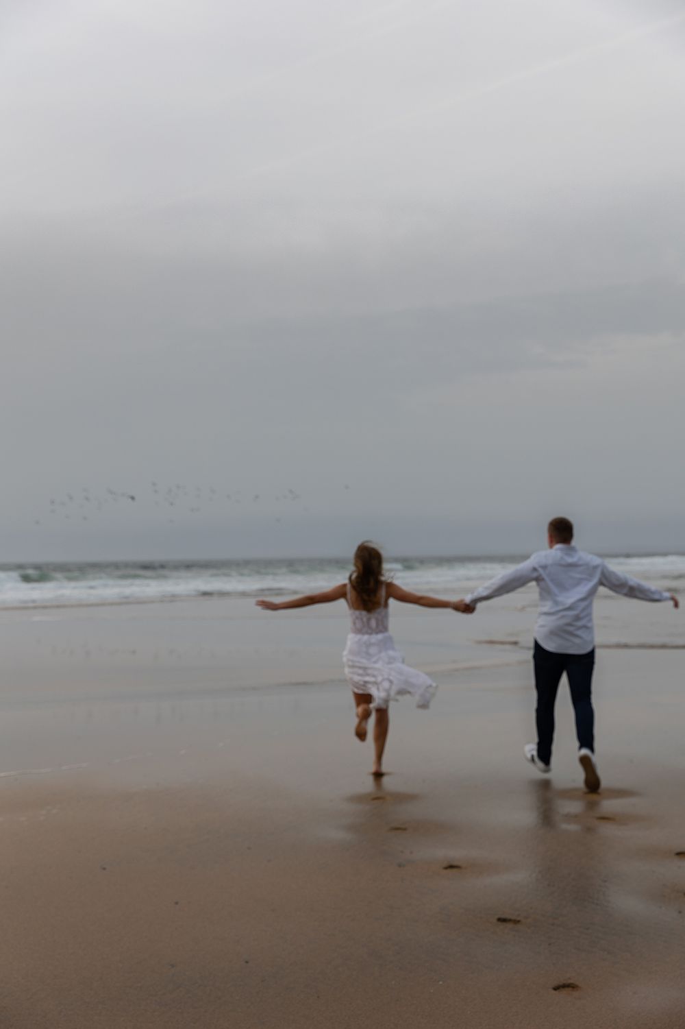 cinematic, storytelling photo of a couple running on a Fanore beach during their adventure photo session in Ireland