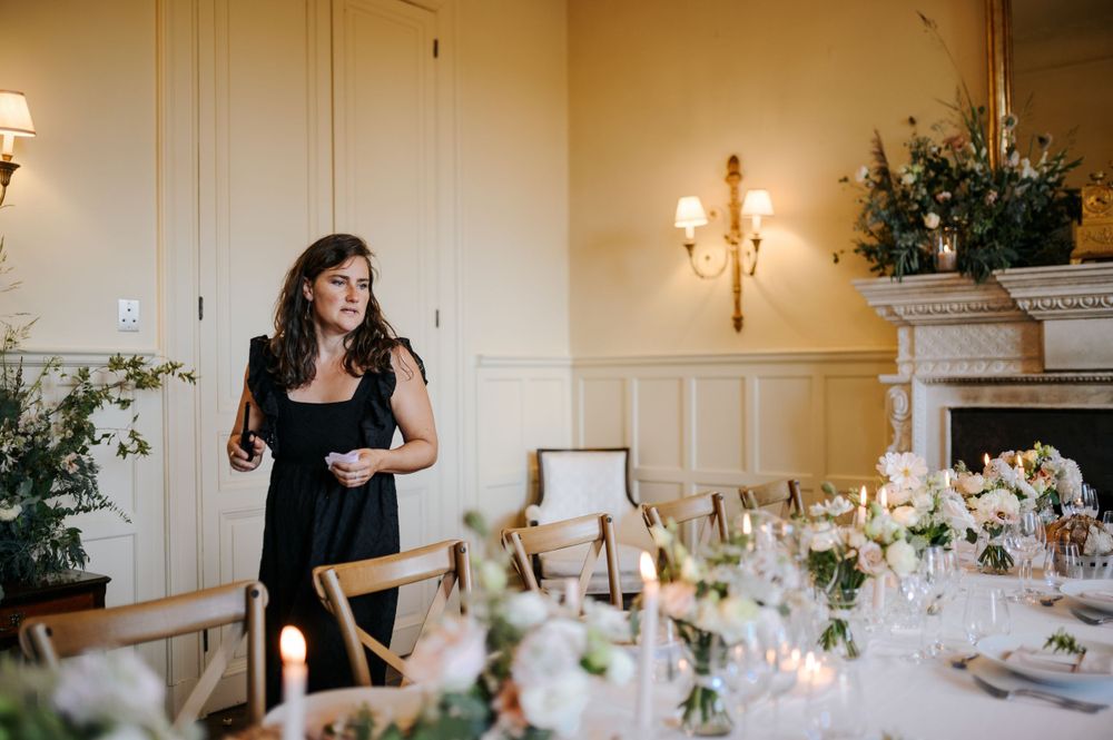 Wedding reception venue with cream walls, wall sconces, and carefully arranged table settings.