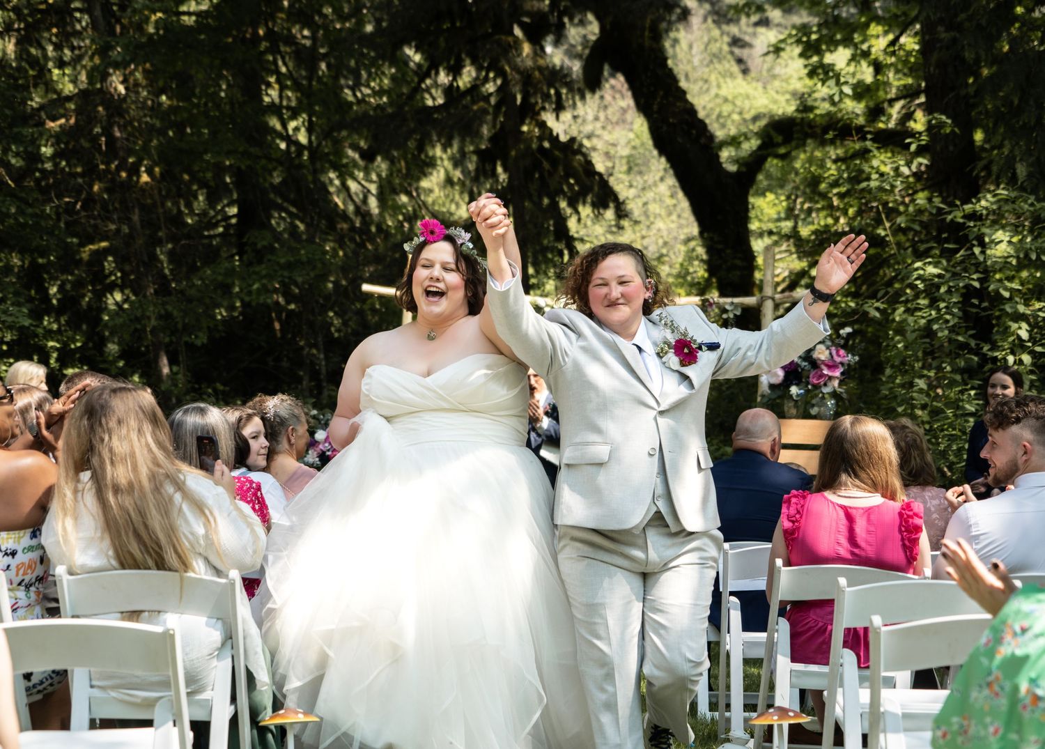 A celebratory recessional moment with the couple raising their arms in joy as guests look on.